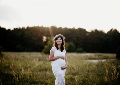 sesja ciążowa przy zachodzie słońca w wianku i białej sukni ciążowej